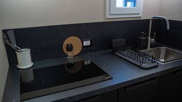 Una cocina moderna con encimera negra, estufa integrada, pileta y ventana sobre la pileta.