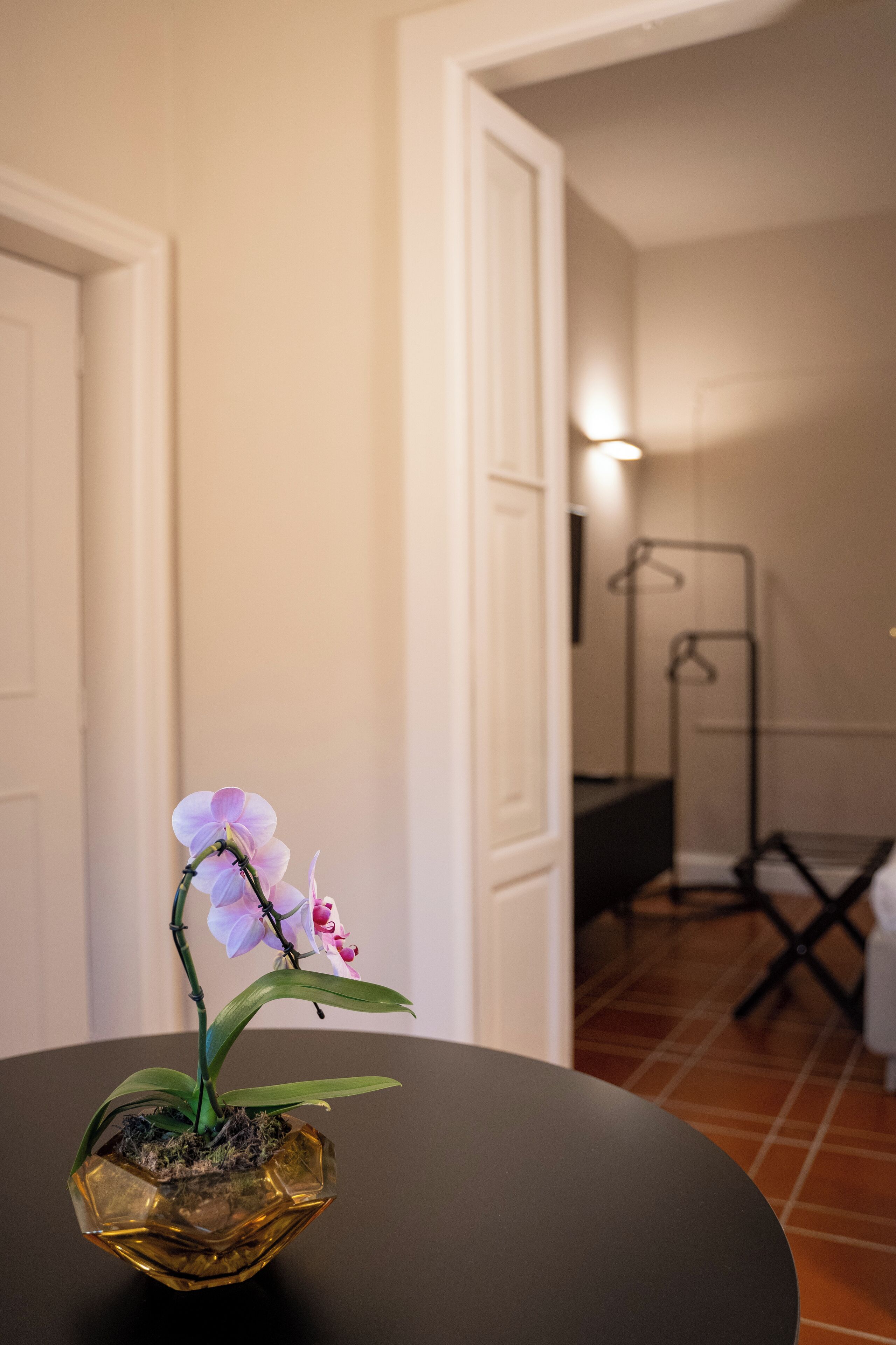 A small orchid in a glass bowl on a round table.