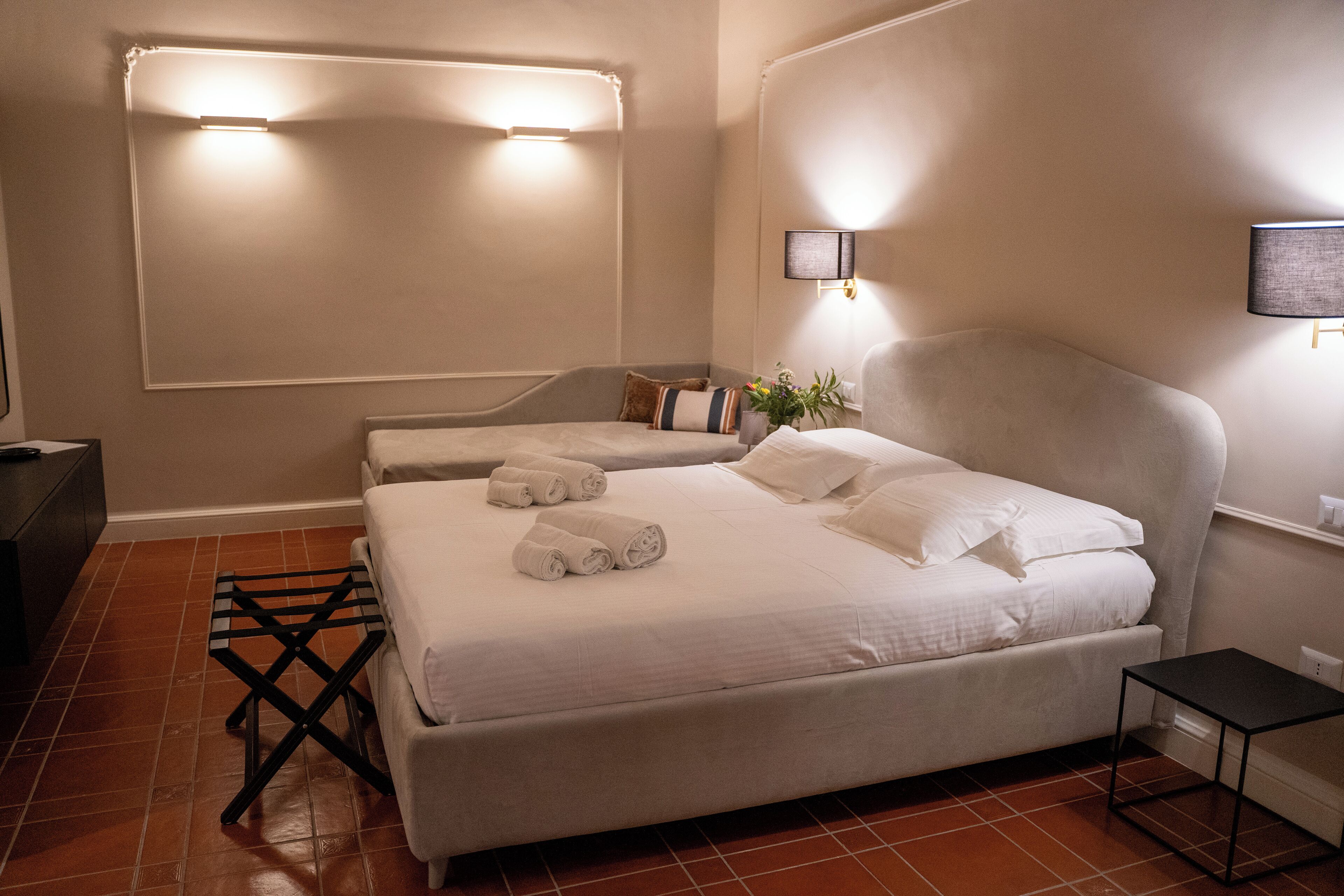 Ein Hotelzimmer mit einem großen Bett, zwei Nachttischen, einem kleinen Tisch und einer Wandlampe.