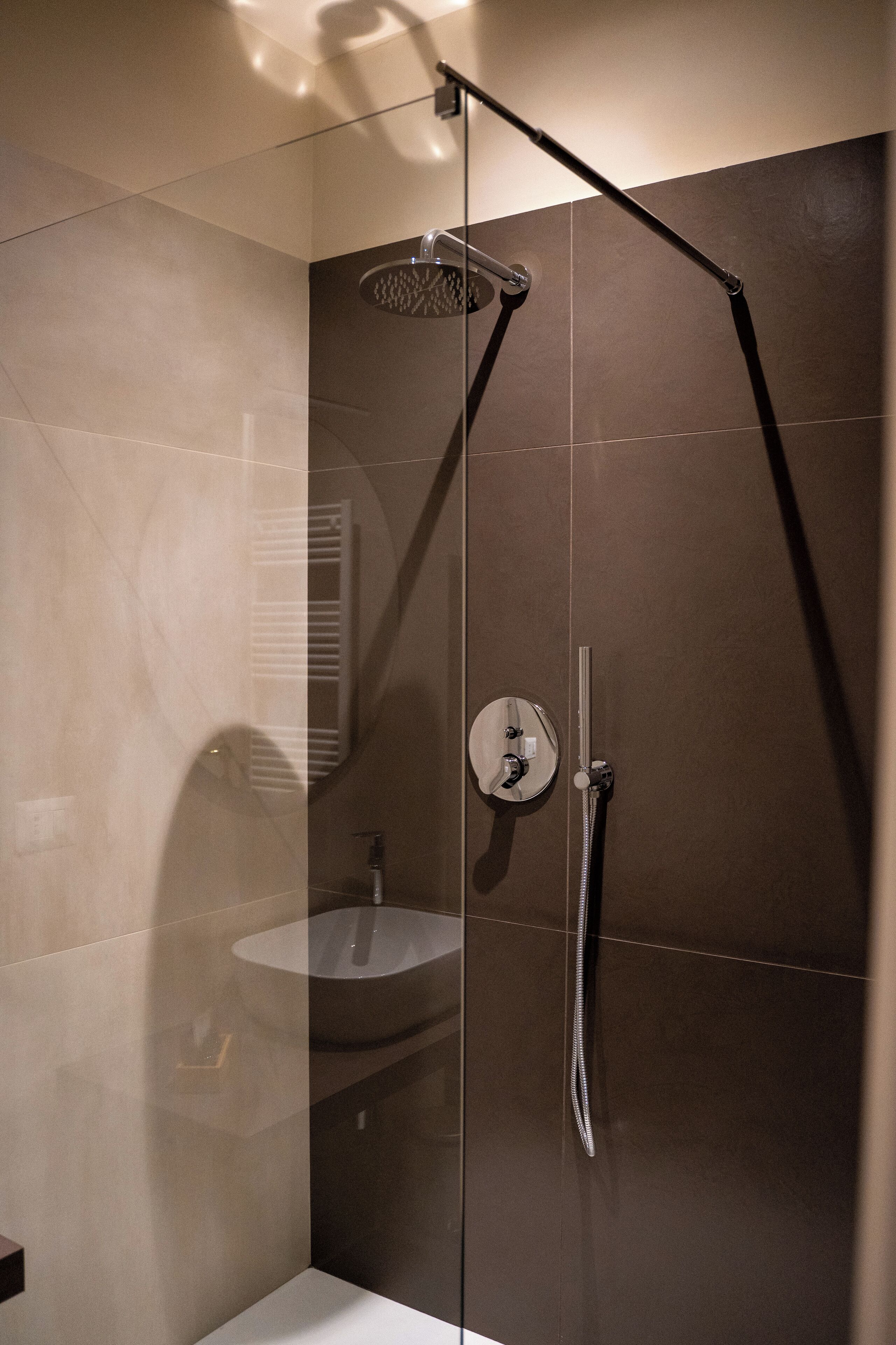 Un baño moderno con ducha envuelta en vidrio, un lavamanos y un perchero para toallas.
