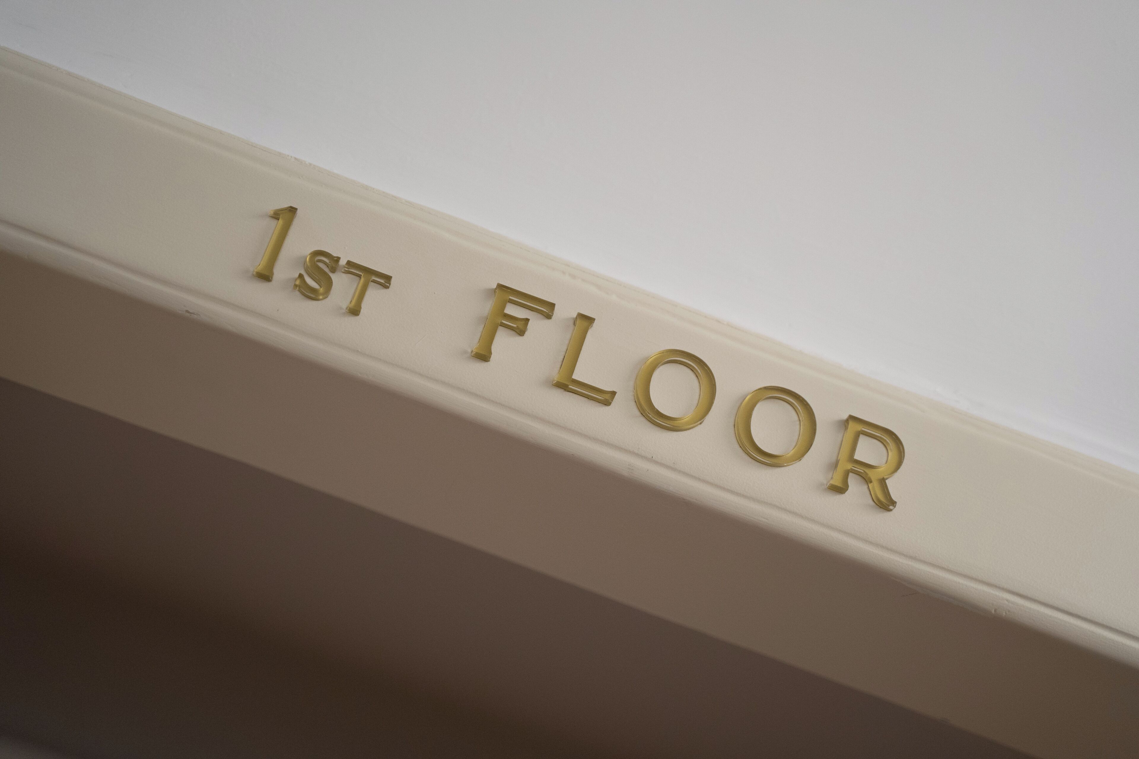 A white wall with gold lettering that reads "1st FLOOR".