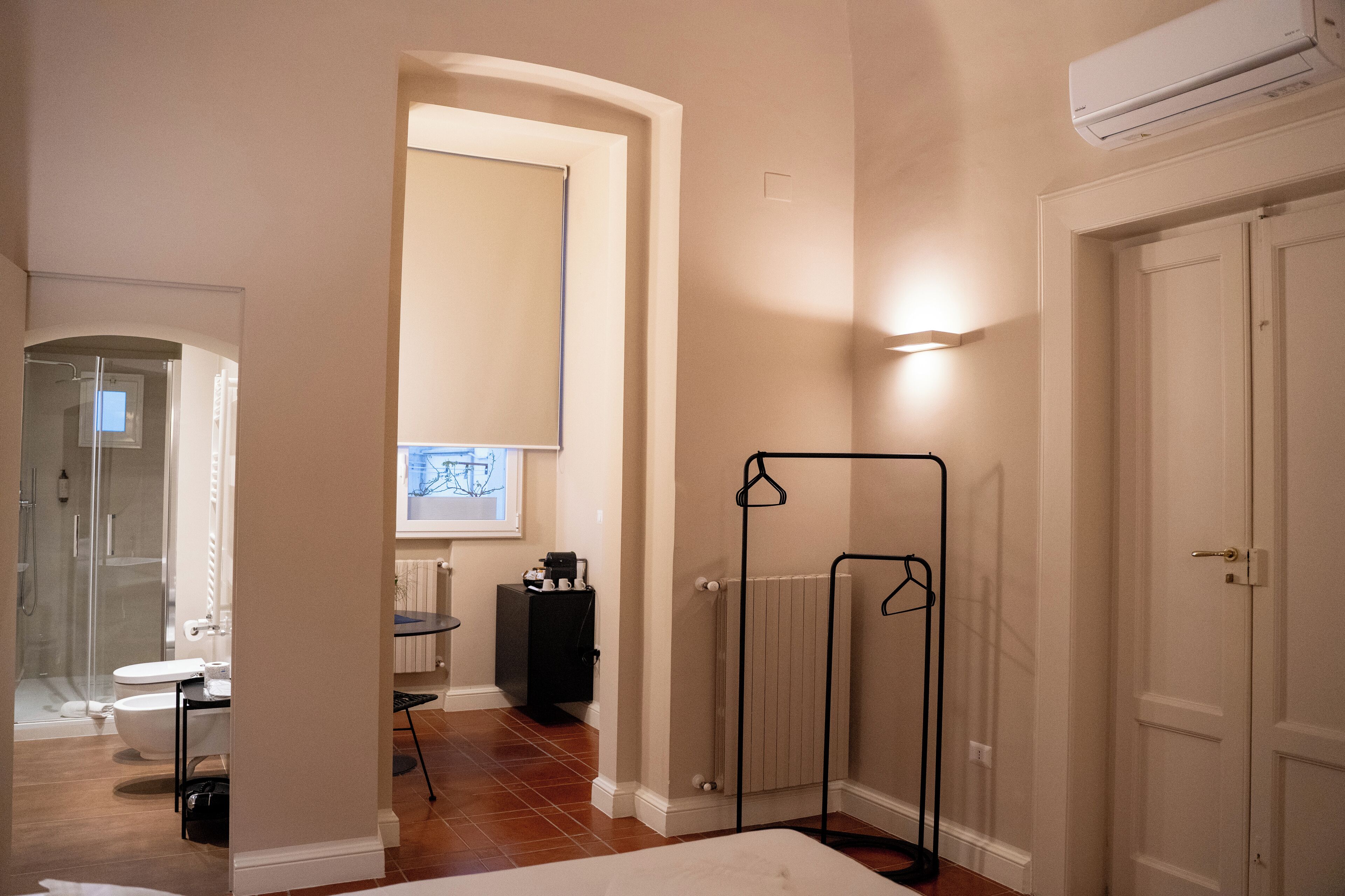 Une salle de bain moderne équipée d’une douche, de toilettes et d’un lavabo. On y trouve également un radiateur et un porte-manteau noir.