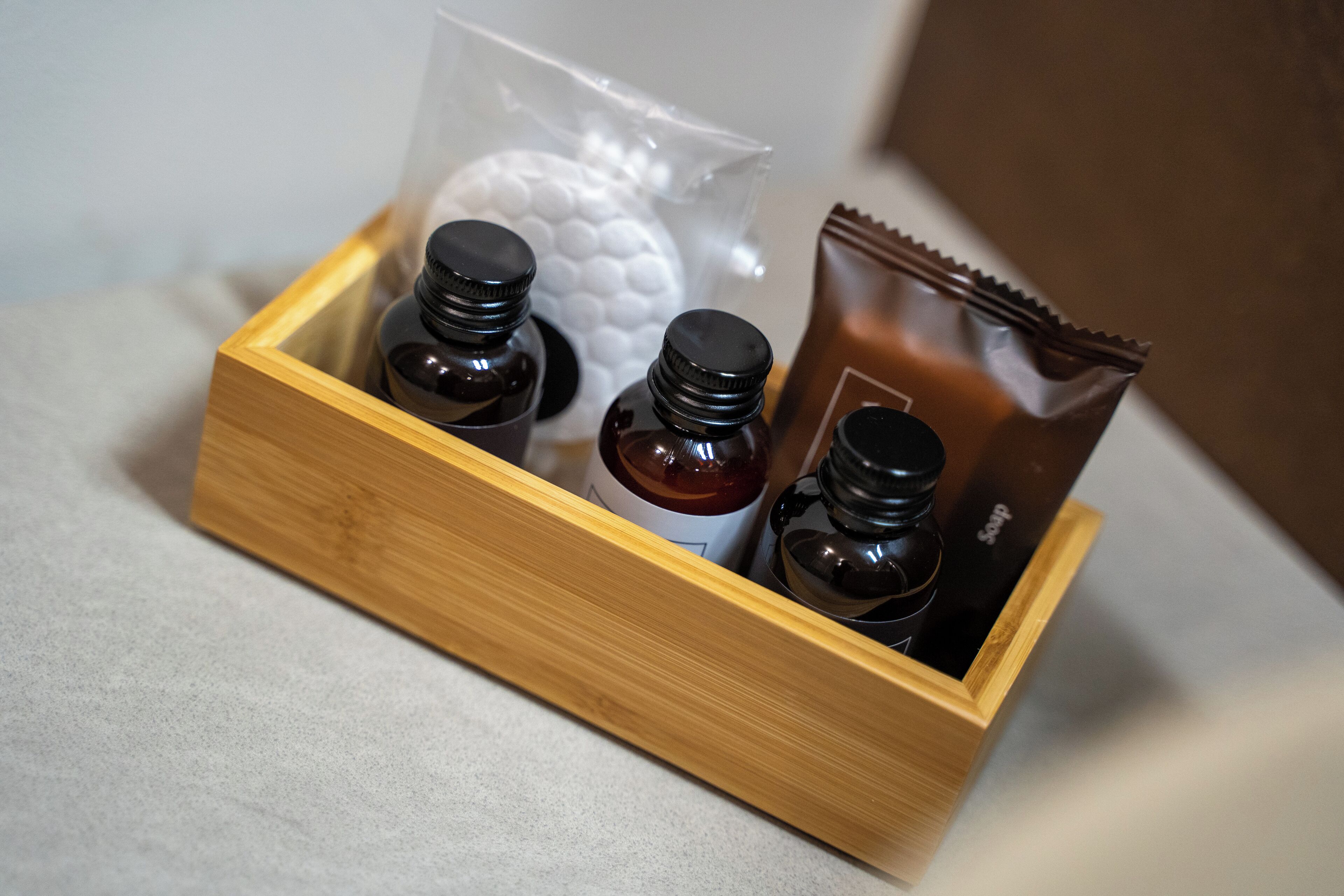 A wooden box containing four small bottles and a plastic bag with a white object.