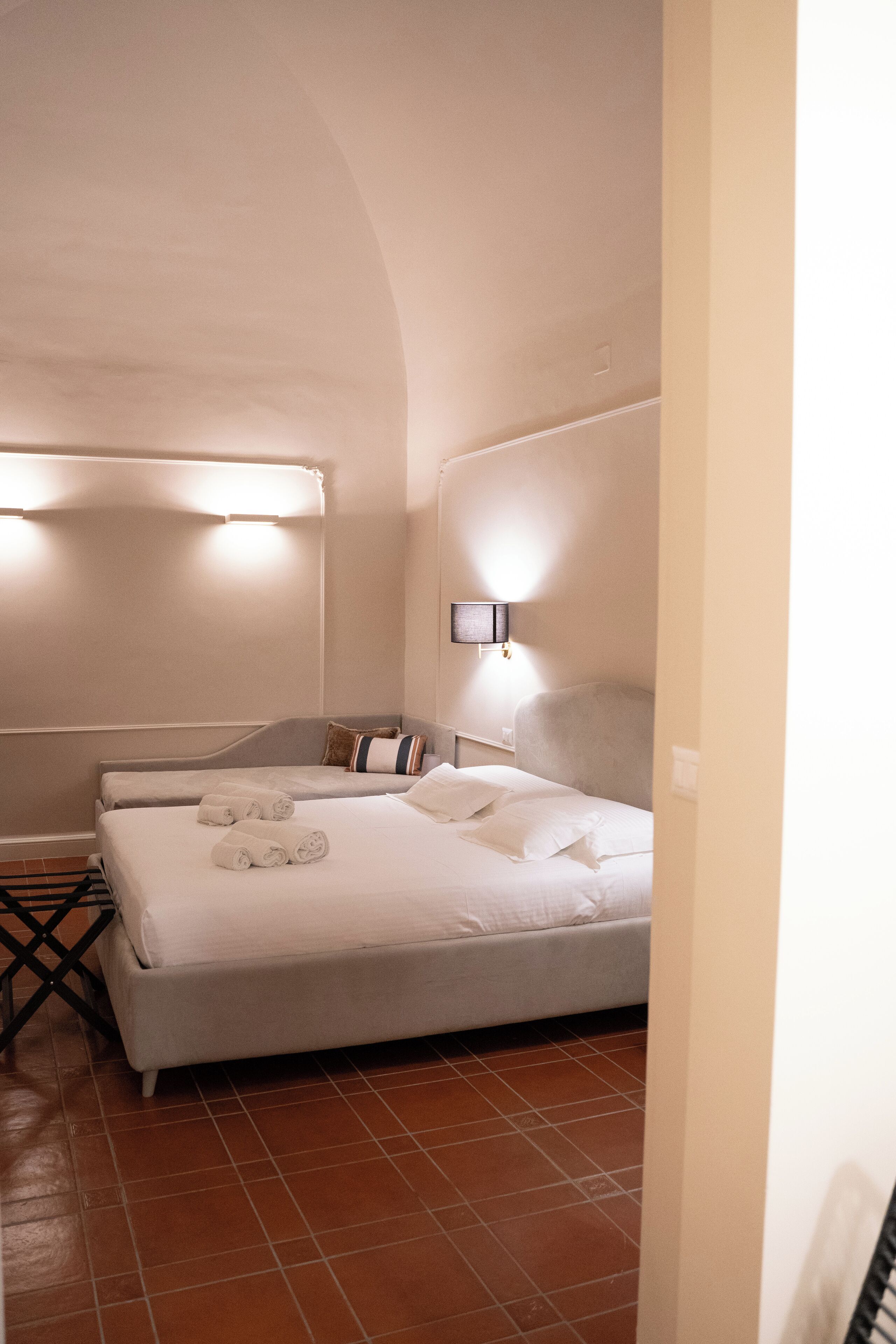 Une chambre d’hôtel avec un grand lit, une table de chevet, une lampe et un luminaire fixé au mur.