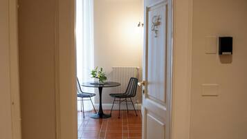 A hallway leading to a dining area with a table and chairs, a radiator, and a door with a light switch.