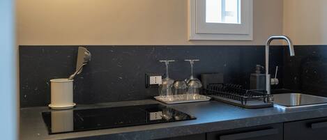 A modern kitchen with a black countertop, a built-in oven, a sink, and a window above the sink.