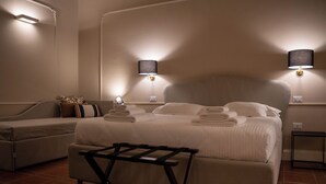 Une chambre d’hôtel avec un lit, un canapé, une petite table et deux lampes fixées au mur.