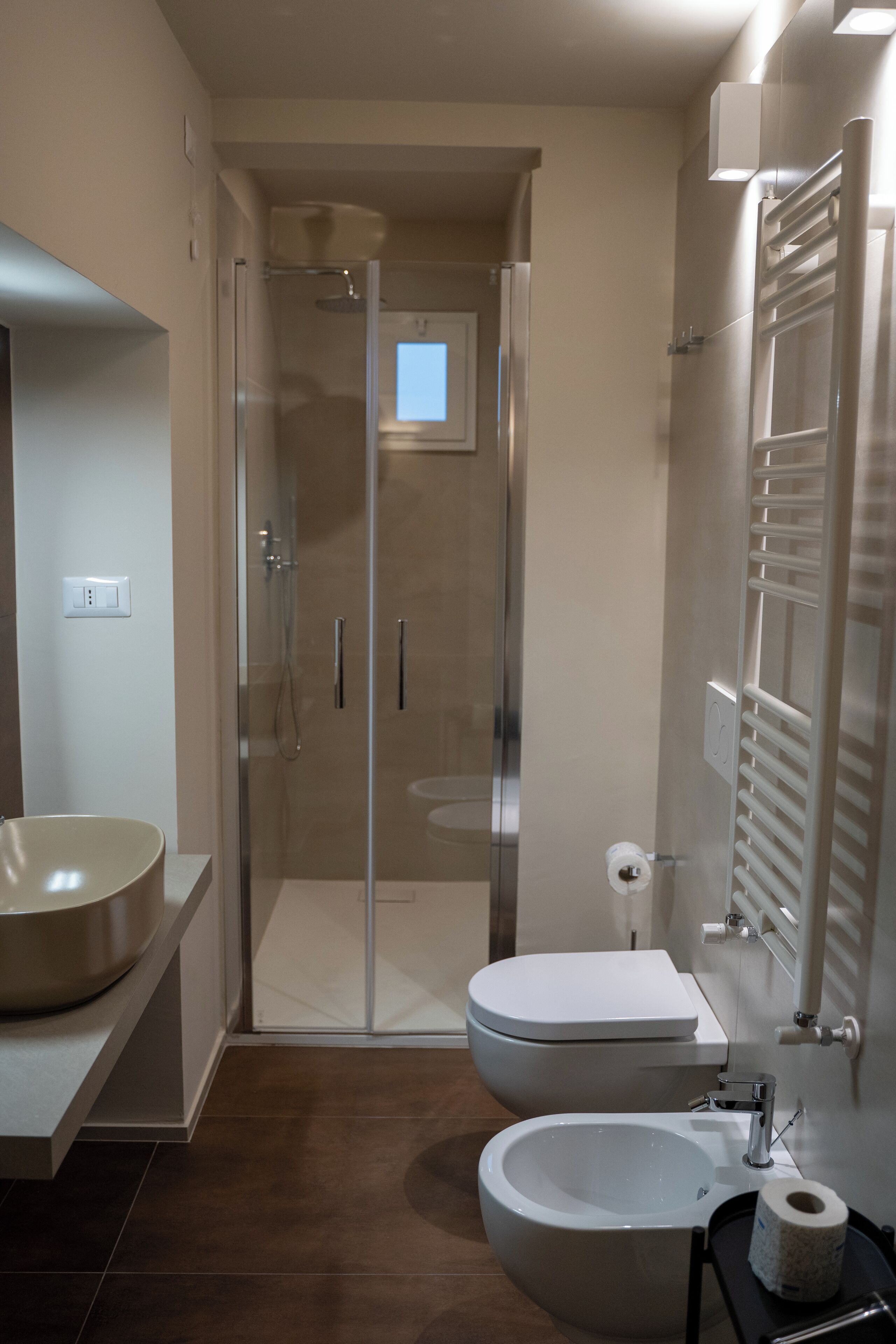 A modern bathroom with a glass-enclosed shower, a large sink, and a toilet.