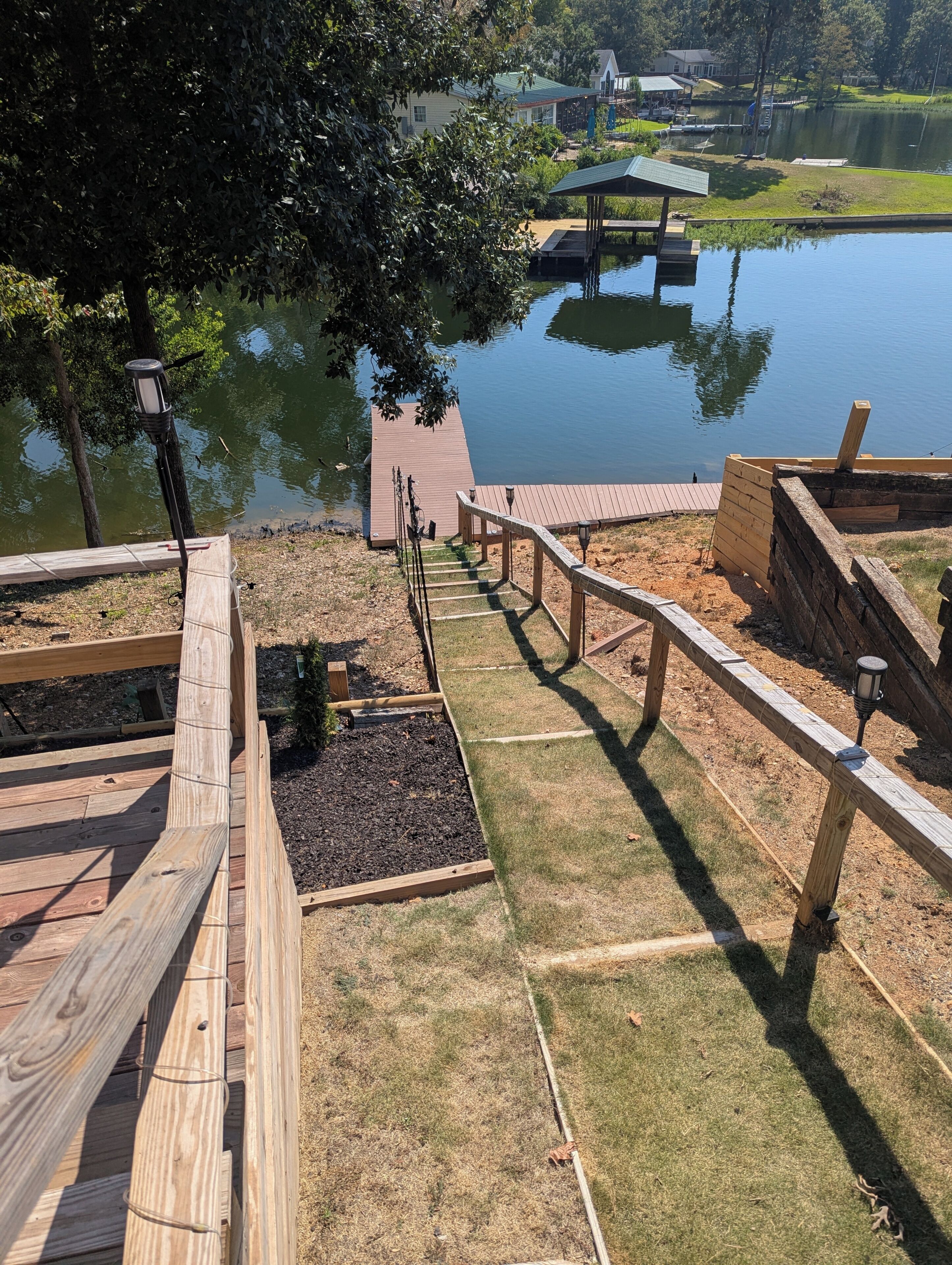 A wooden deck with a view of a lake, a gazebo, and a dock.