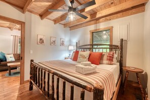 Une chambre confortable avec un lit en bois, un ventilateur de plafond et une fenêtre donnant sur un paysage verdoyant.