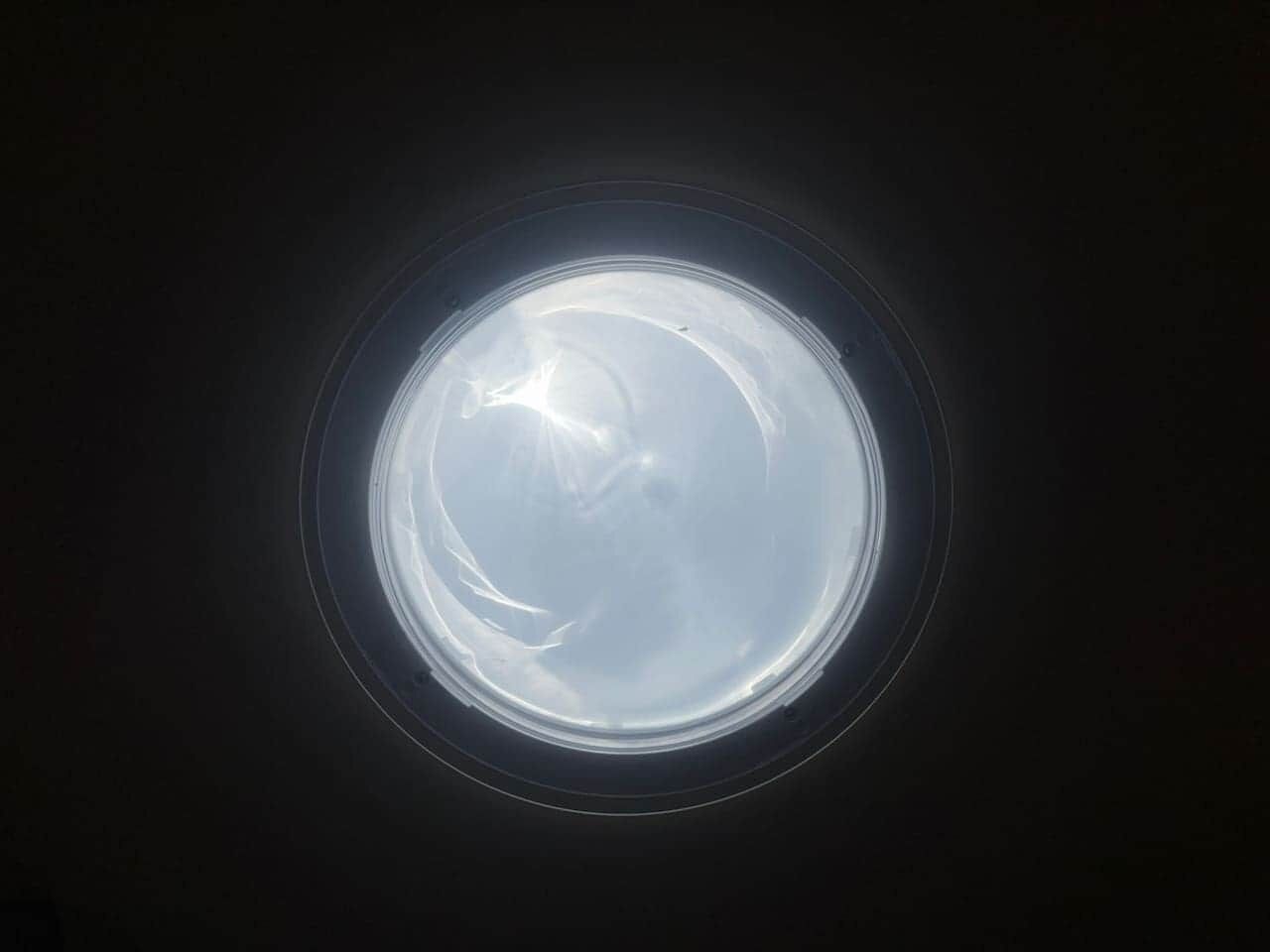 Una ventana redonda con una vista despejada del cielo.