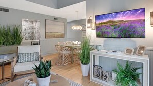 Una sala de estar moderna con comedor, un televisor de pantalla plana grande y plantas decorativas.