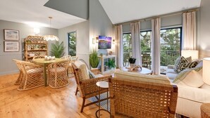 Una habitación con una mesa de comedor, sillas de mimbre, un sofá y vistas al exterior.
