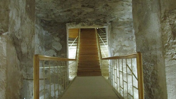 A stone-walled corridor with a wooden staircase leading to a higher level. - Furnished apartment in Minya with archaeological tours (Minya Governorate)