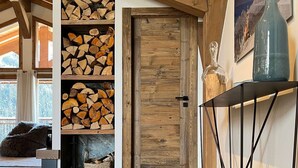 A wooden interior with a built-in fireplace, a wooden door, and a black metal table. - T4 spacieux avec cheminée (Peisey-Nancroix)