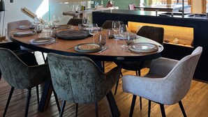 A dining area with a wooden table set for six, surrounded by upholstered chairs. A painting of a snowy scene is on the wall, and the room has a high ceiling with exposed wooden beams. - T4 spacieux avec cheminée (Peisey-Nancroix)