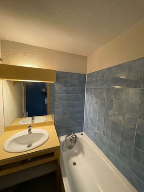 Une salle de bain avec une baignoire blanche, un lavabo et un miroir.