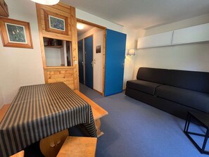 Una stanza con un tavolo in legno, un divano nero e una porta blu.