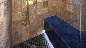 A shower area with patterned tiles and a bench. - Chalet at the foot of the ski resorts with spa (Landry)