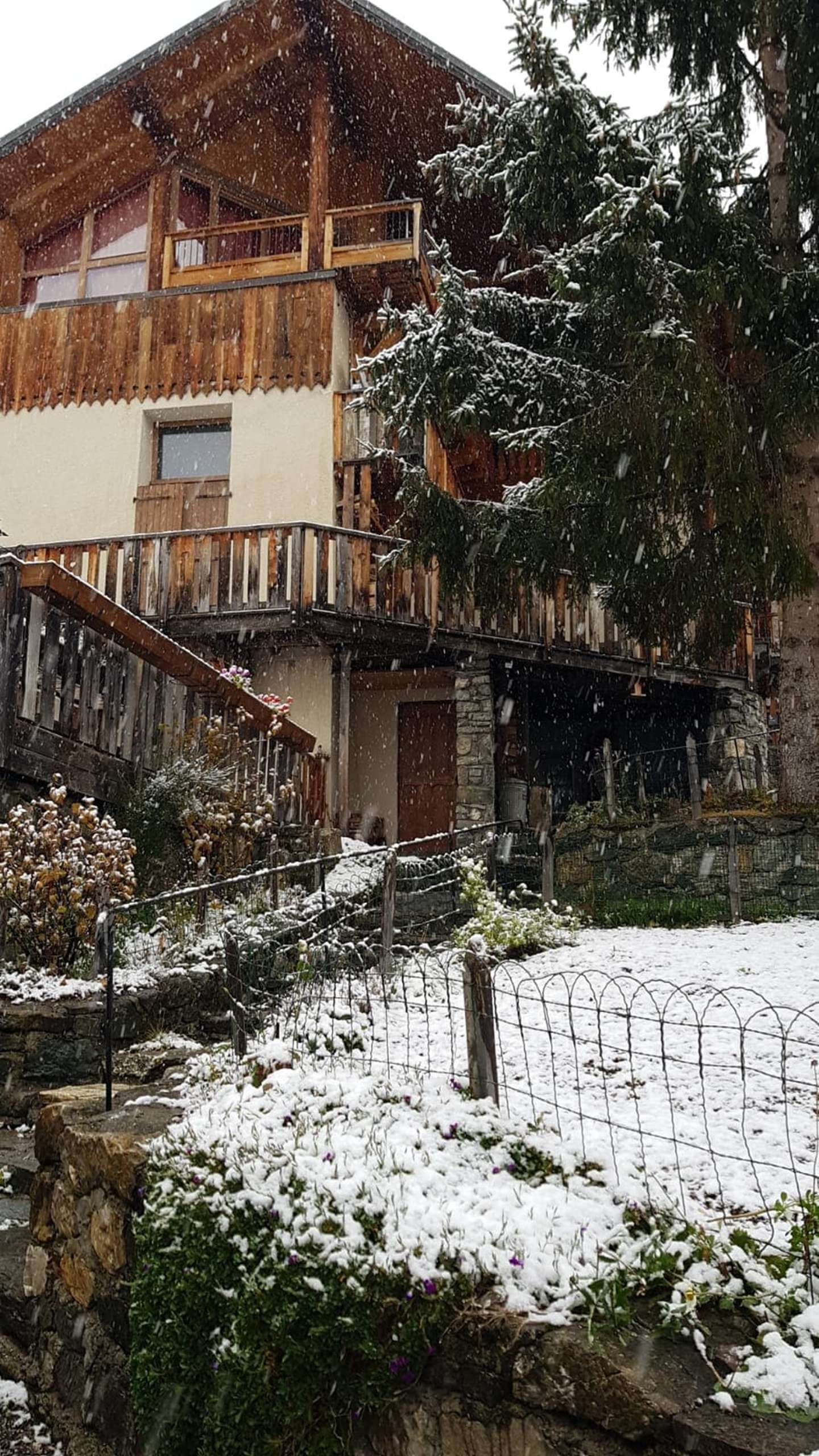 Edificio cubierto de nieve con balcón de madera y pared de piedra.