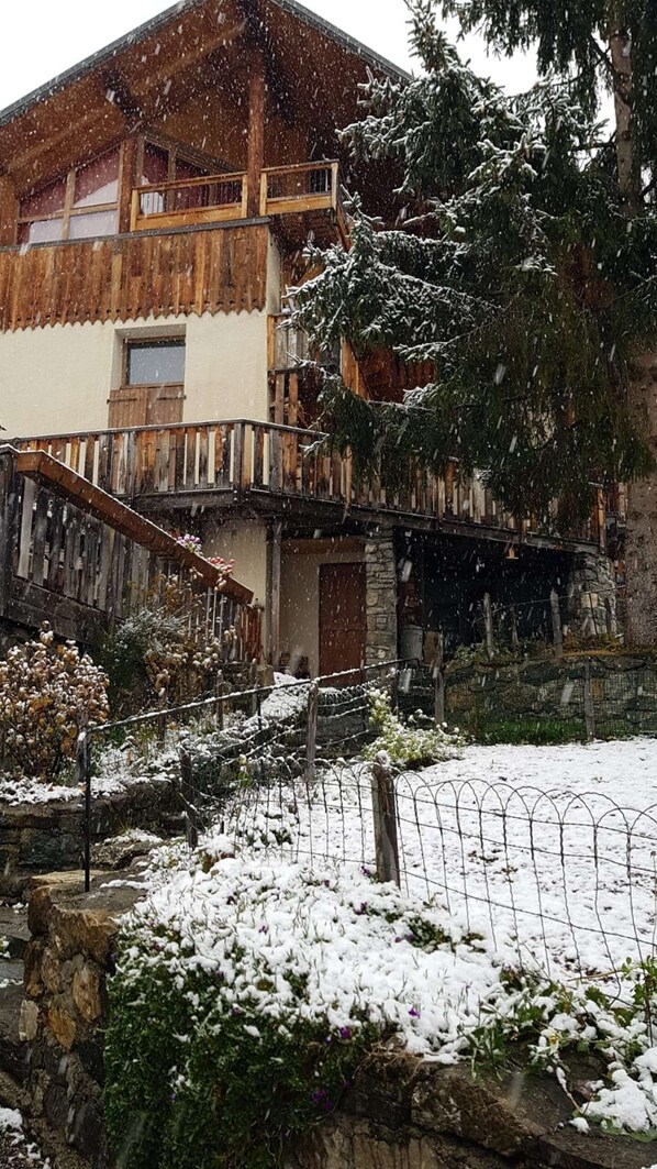A snow-covered building with a wooden balcony and a stone wall.