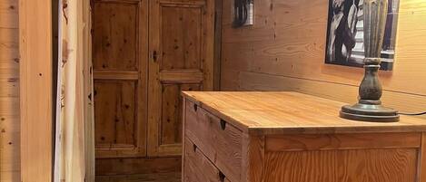 Un intérieur en bois comprenant un bureau, des tiroirs, une lampe et une porte ornée d’un motif en forme de cœur.