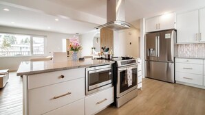 Una cocina moderna con electrodomésticos de acero inoxidable, armarios blancos y una isla grande con horno empotrado.
