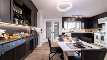 A modern kitchen with dark cabinetry, a central island, and a dining area with a white table set for four.