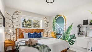 A bedroom with a bed, bedside table, and a wall mural. - Pac-Man fun, pet-friendly comfort, and cozy vibes near Downtown Edmonton (Edmonton)