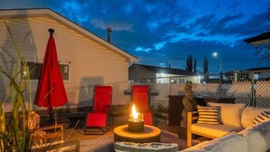 A cozy outdoor seating area with a fire pit, red chairs, and a white couch. - Pac-Man fun, pet-friendly comfort, and cozy vibes near Downtown Edmonton (Edmonton)