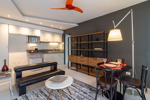 Una cocina moderna con armarios blancos, un banco negro y un comedor con una mesa preparada para dos.