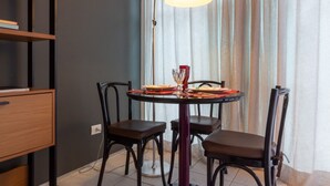 Un comedor con una mesa redonda, cuatro sillas, una lámpara colgante, una estantería y un tapete estampado.