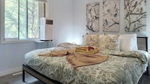 A bedroom with a large bed, a window with a view of trees, and three wall-mounted bird paintings. - Family-friendly comfort near Misericordia Hospital and West Ed Mall (Edmonton)