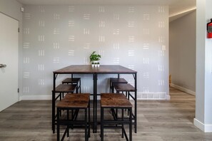 Un comedor con mesa de madera y bancos, una planta en maceta y un extintor en la pared.