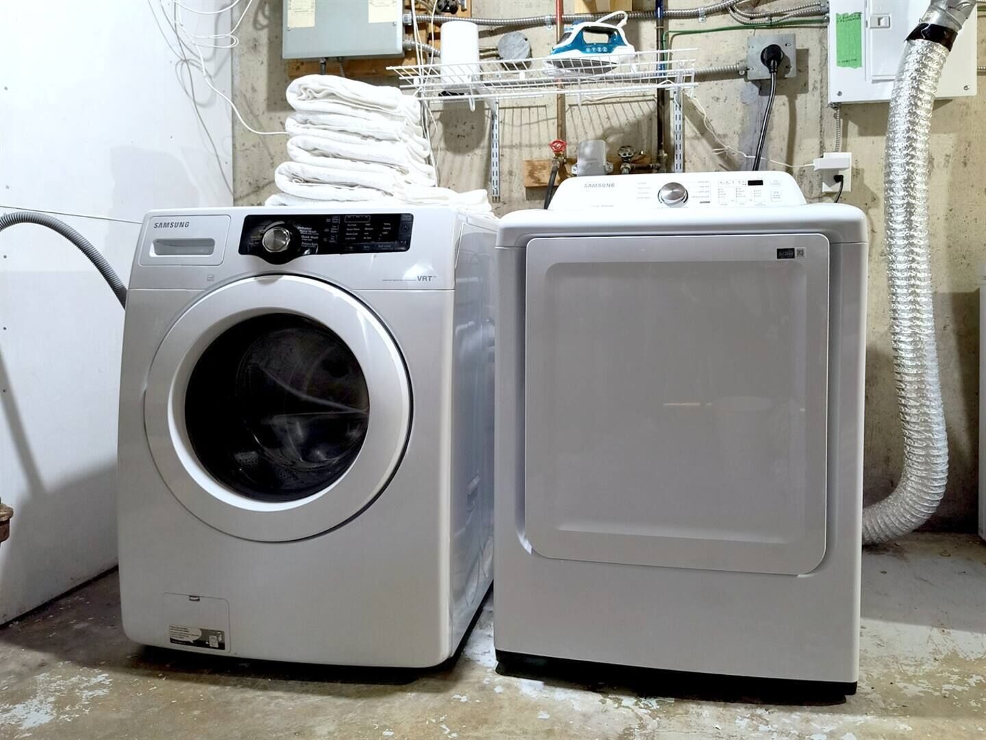 Une machine à laver à chargement frontal et un sèche-linge, placés côte à côte dans une buanderie.