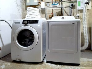 Une machine à laver à chargement frontal et un sèche-linge, placés côte à côte dans une buanderie.