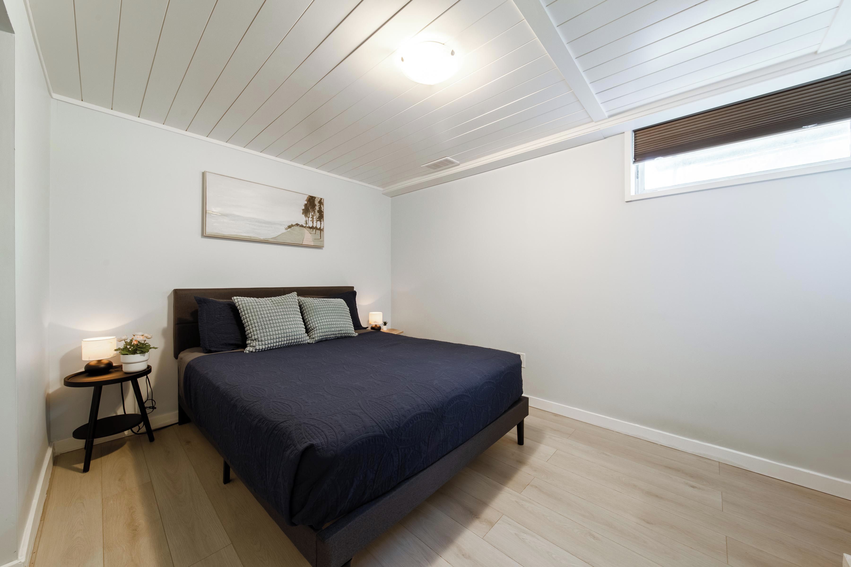 A bedroom with a bed, a nightstand, a lamp, and a window with blinds.
