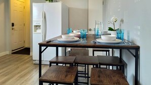 A dining area with a wooden table set for four, a refrigerator, and a door leading to another room. - Family-friendly comfort near Misericordia Hospital and West Ed Mall (Edmonton)