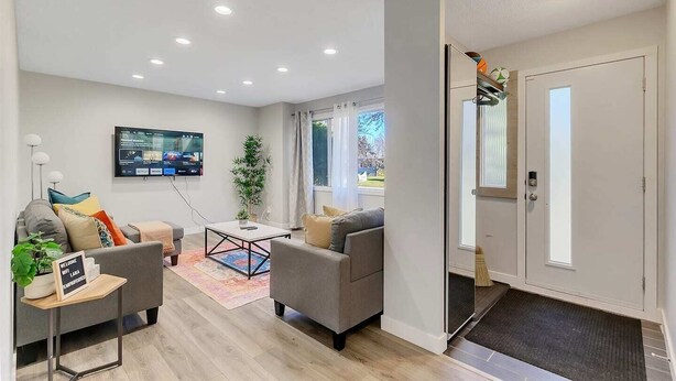 A modern living room with a sofa, coffee table, and a TV mounted on the wall. - Family-friendly comfort near Misericordia Hospital and West Ed Mall (Edmonton)