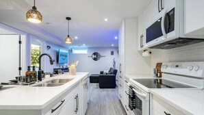 Een moderne keuken met witte kastjes, een centraal eiland en een ingebouwde magnetron.