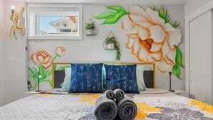 Een slaapkamer met een groot bed, een raam en een wanddecoratie.