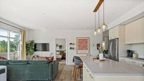 Een moderne keuken met een centraal eiland, ingebouwde apparatuur en een zithoek met een bank en stoelen.