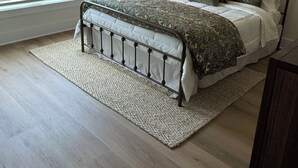 Un dormitorio con una cama, una mesita de noche, una lámpara, un cuadro y una ventana con persianas.