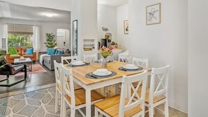 Et moderne spiseområde med et træbord dækket til fire personer, omgivet af hvide stole.