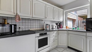 A kitchen with white cabinets, a microwave, an oven, and a coffee maker.