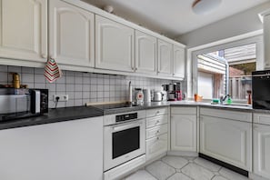 Eine Küche mit weißen Schränken, einer Mikrowelle, einem Backofen und einer Kaffeemaschine.