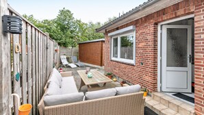 A patio area with a wicker sofa, a table, and a chair.