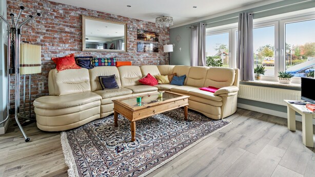 A living room with a brick wall, a sofa set, a coffee table, and a large window.