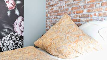 Cama com roupa de cama estampada, parede de tijolos e um mural floral.