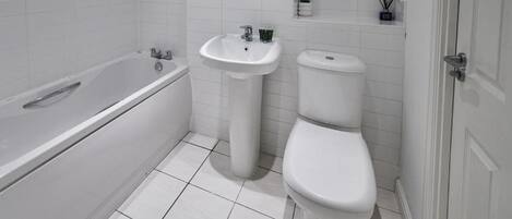 A bathroom with a bathtub, two sinks, and a toilet.